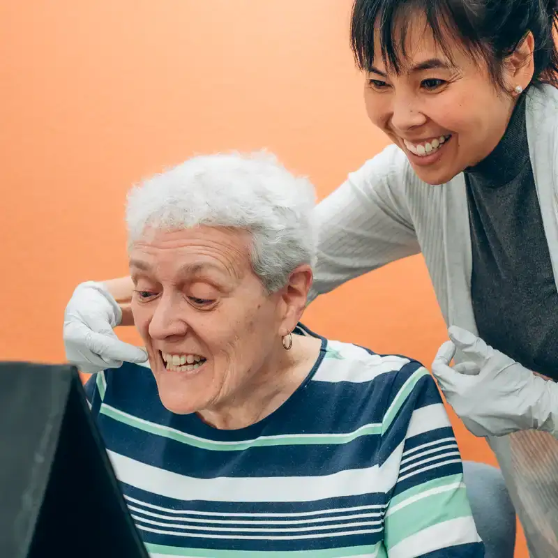 Compassionate speech therapist assisting elderly woman with speech therapy exercises in a comfortable setting.