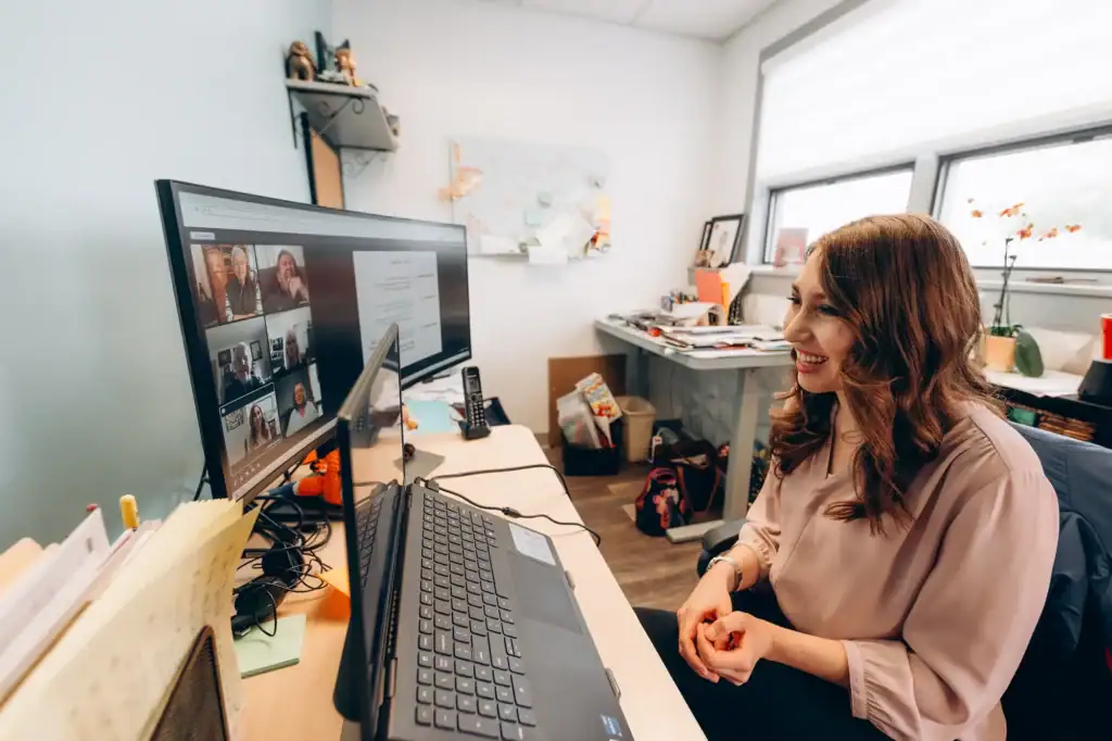 Remote speech therapy session with a smiling woman engaging via video call in an office setting.