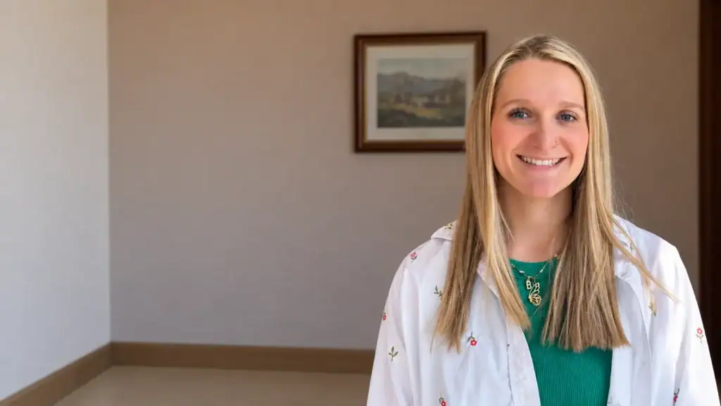 Portrait of Brooklyn Vincent, a speech therapist in Montana, smiling in her office with a framed landscape picture behind her.